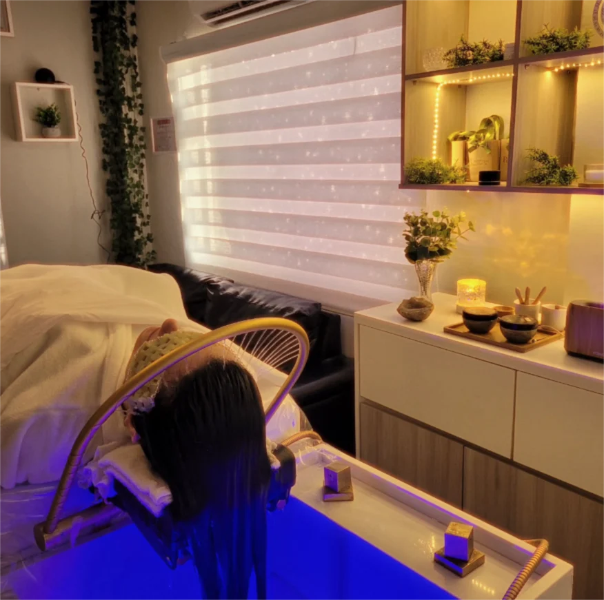 Sala de atendimento: maca com lavatório iluminado, prateleiras com plantas e velas acesas